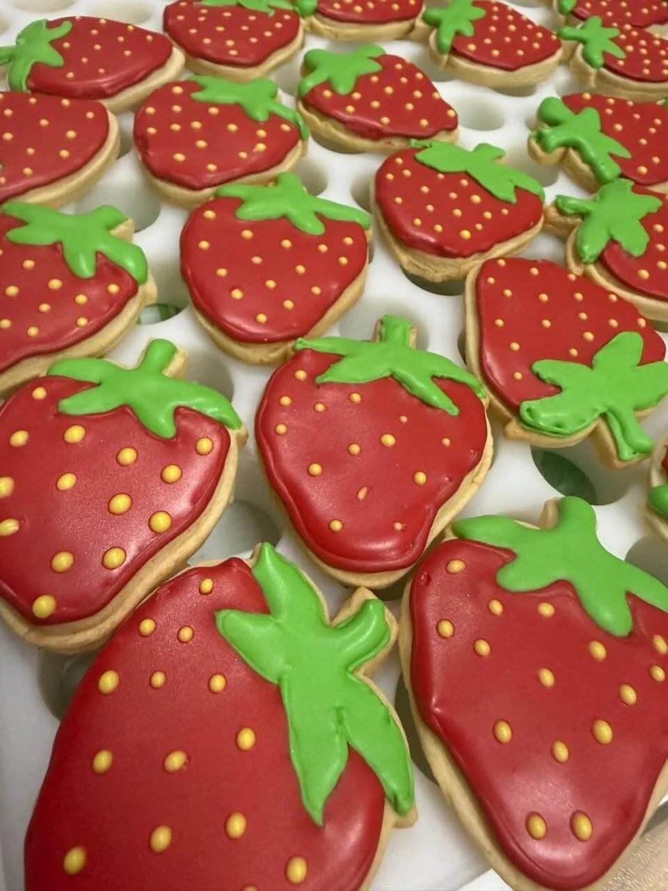 Biscoitos amanteigados em formato de morango decorados com glacê real