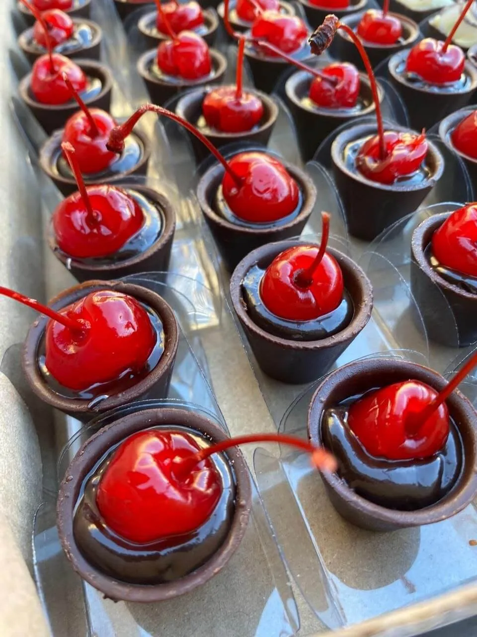 Doces finos em copinhos de chocolate com cereja e calda