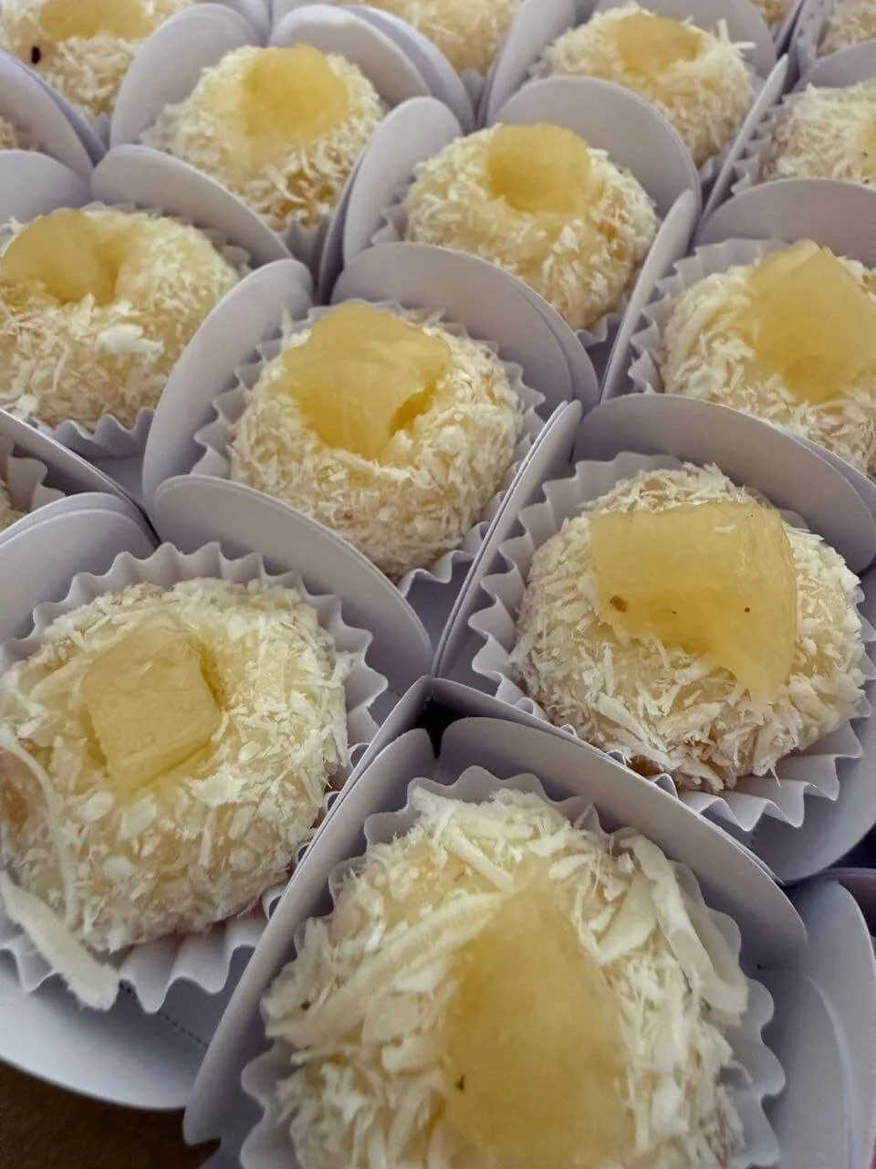 Docinhos de coco com pedaço de abacaxi em forminhas