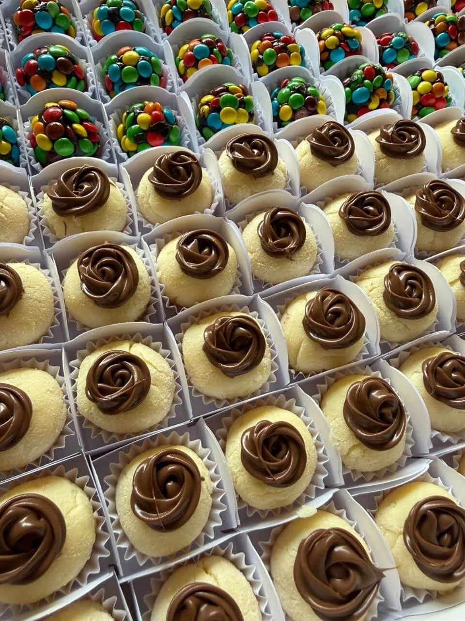 Docinhos de leite ninho com rosa de Nutella ao lado de brigadeiros de confete