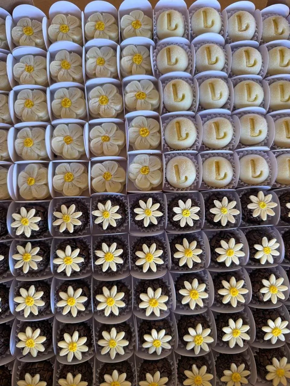 Docinhos modelados em formato de flor e da letra L, e brigadeiros com margaridas de chocolate branco
